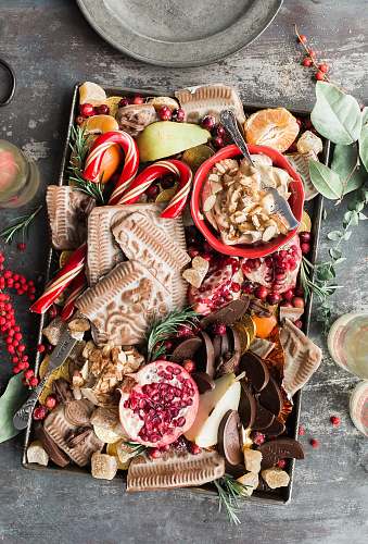 holiday variety of sliced fruits, cookies, and chocolates on gray steel tray food