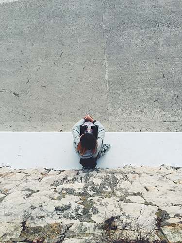 people top view of person sitting near gray rock wall during daytime person