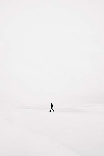 white person walking on snowfield black-and-white