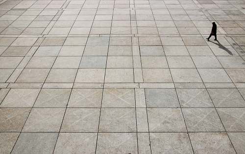 grey man walking on tiled ground at daytime nathan phillips square