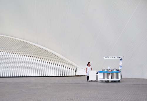 fresh woman wearing white dress and black pants near stall architecture