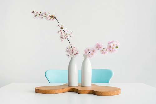 table two pink petaled flowers in white vases on brown wooden surface flower