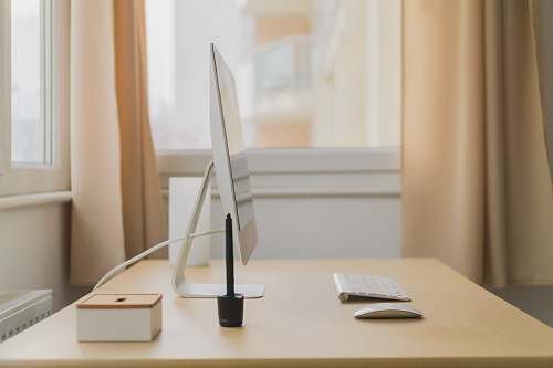 office Apple iMac on wooden desk near window workspace