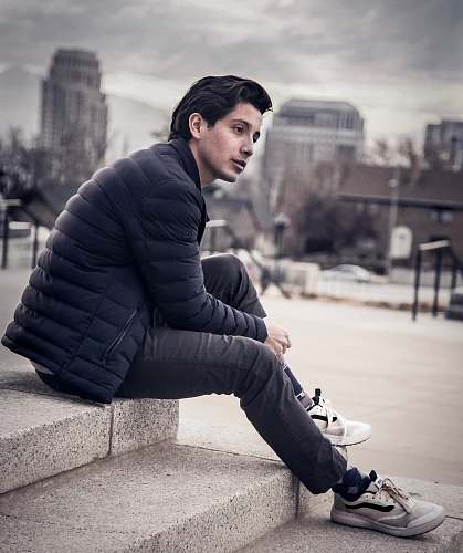footwear man sitting on concrete surface apparel