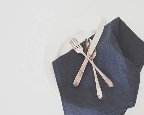 linen gray fork, spoon, and butter knife on plate with black table napkin table