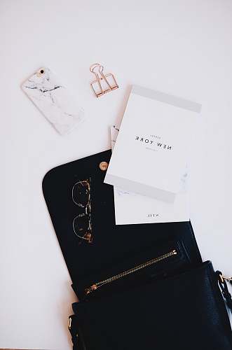 desk gold framed sunglasses, black phone case near gold clip grey