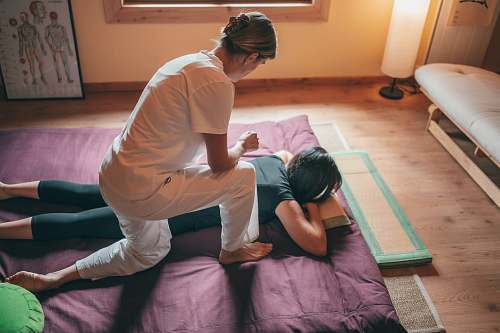 person man in white t-shirt and white pants lying on purple bed massage
