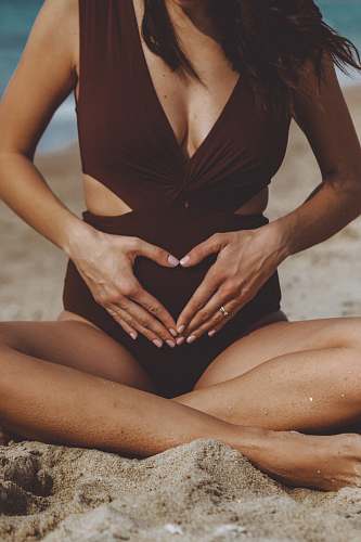 human woman in black one piece swimsuit sitting on sand during daytime patient