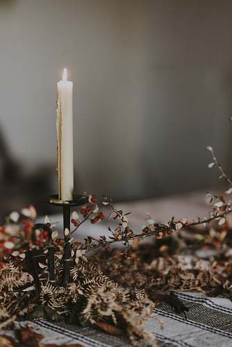 fire lighted candle on candlestick on top of table grey