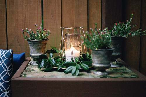 pottery lighted candle on table beside pots flora