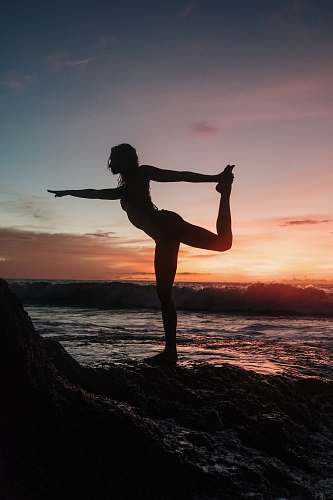  silhouette of woman standing on rock during sunset 