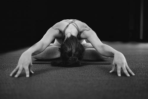  woman in white tank top bending her body on floor 