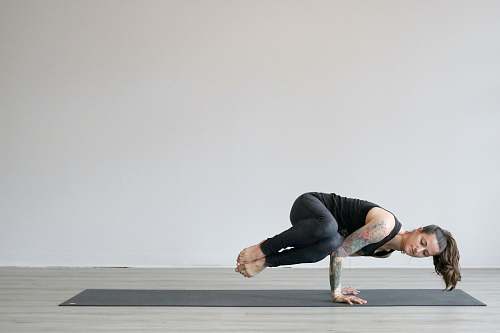human woman in black tank top and gray leggings doing yoga exercise