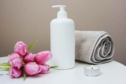 beauty white plastic pump bottle beside pink tulips and gray towel flora