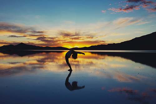 mountain silhouette photography of woman doing yoga ocean