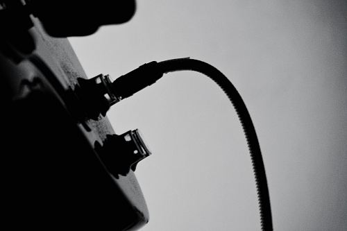 A black-and-white shot of a wire plugged in into a guitar