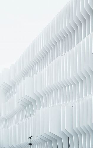 A security camera near parallel white ribs in a building facade in Madrid