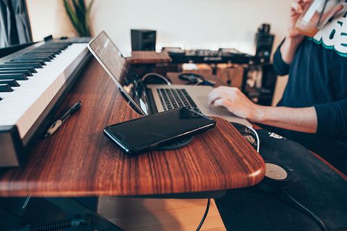 black Android smartphone beside MacBook Pro on top of brown table