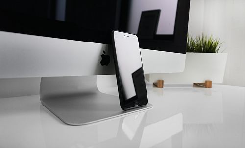 black iPhone 7 leaning on silver iMac