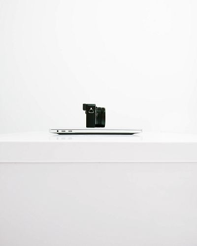 black mirrorless camera on top of MacBook
