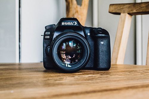 Canon DSLR camera on brown wooden table during daytime