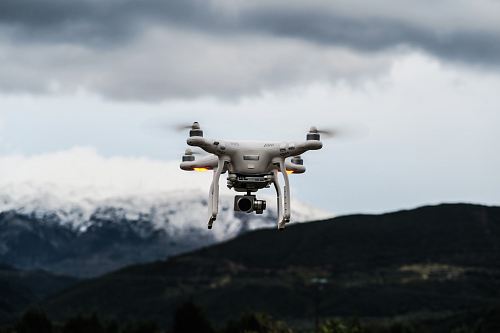 flying white quadcopter drone at daytime