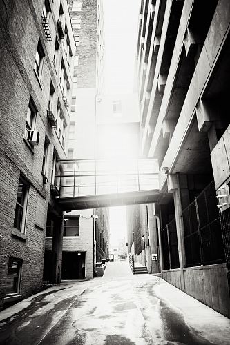 grayscale photo of pathway between buildings