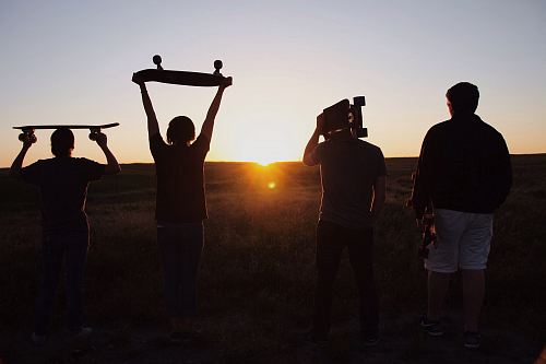 group of people holding skateboards under sunset