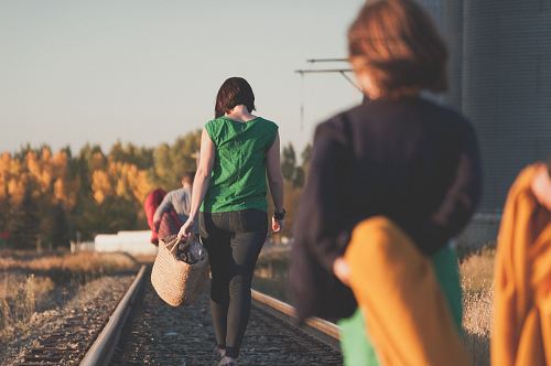 group of people walking on train tracks during sunrise