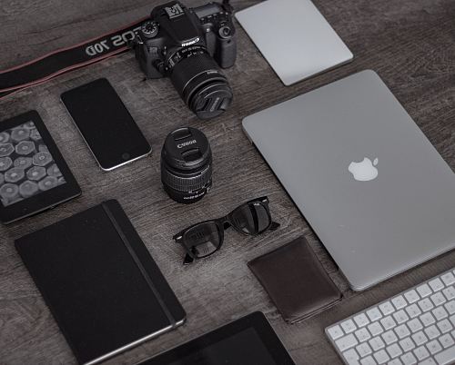 iPad near sunglasses, wallet, and DSLR camera