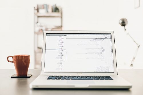 MacBOok Pro beside brown mug