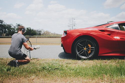 man behind car holding microphone measuring sound