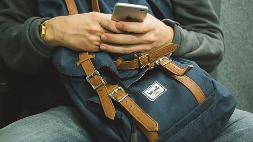 man holding his phone while sitting on chair