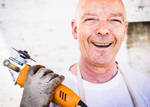 man holding orange angle grinder
