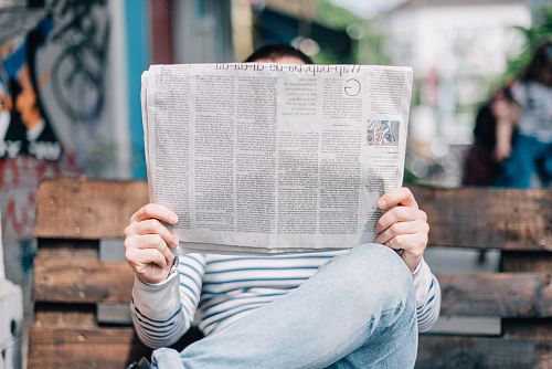 man sitting on bench reading newspaper