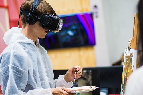 man wearing black virtual reality headset while painting near brown wall