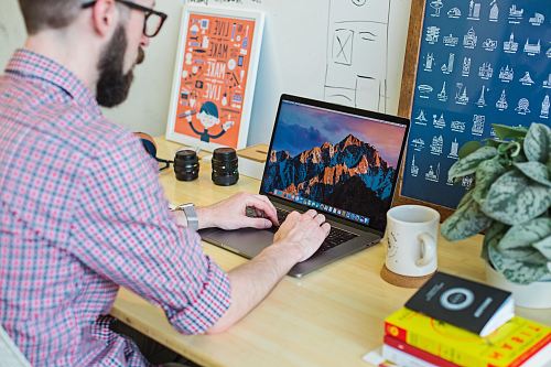 man wearing collared shirt using MacBook