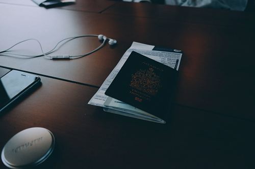 passport beside earphones on surface