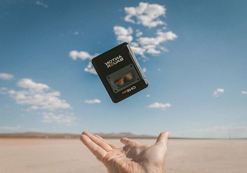 person catching black Anton Bauer device under blue sky during daytime