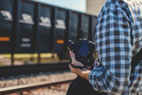 person holding DSLR camera near cargo container during daytime