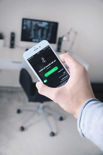 person holding iPhone showing Spotify application