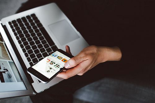 person holding smartphone and laptop