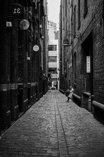 person leaning back on brick building in the alley