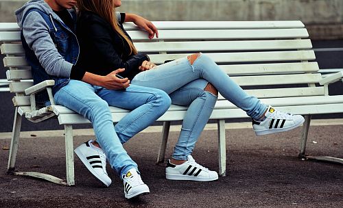 photo of couple sitting on white bench