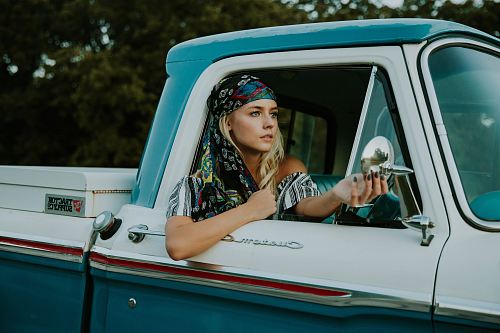 photography of woman holding side mirror in white and green 2-door pickup truck