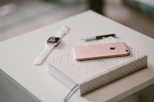 rose gold iPhone 6s on book near Apple watch