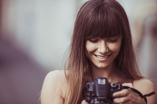 selective focus photography of smiling woman holding camera