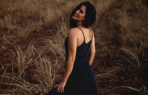 selective focus photography of woman in black dress standing at grass field