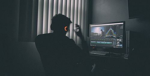 shallow focus photography of man listing to music in front of the computer