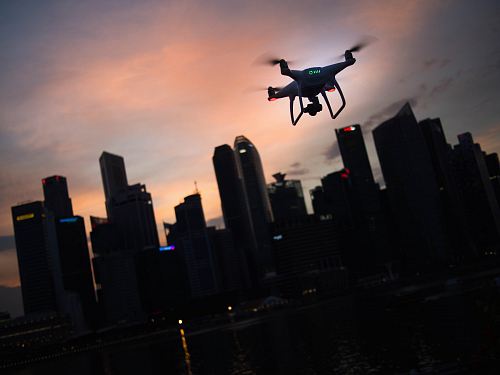 silhouette of quadcopter drone hovering near the city